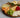 Cheese board with sliced cheese, green grapes, raspberries, tangerine slices, walnuts, and bread on wooden platter